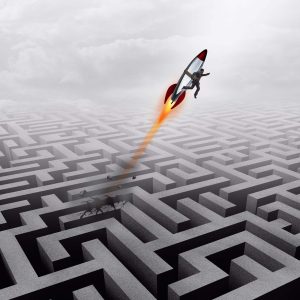Business success concept and successful clever businessman motivation metaphor as a man breaking out of a maze with a rocket ship going upward towards a career goal getting past a metaphoric labyrinth puzzle obstacle.